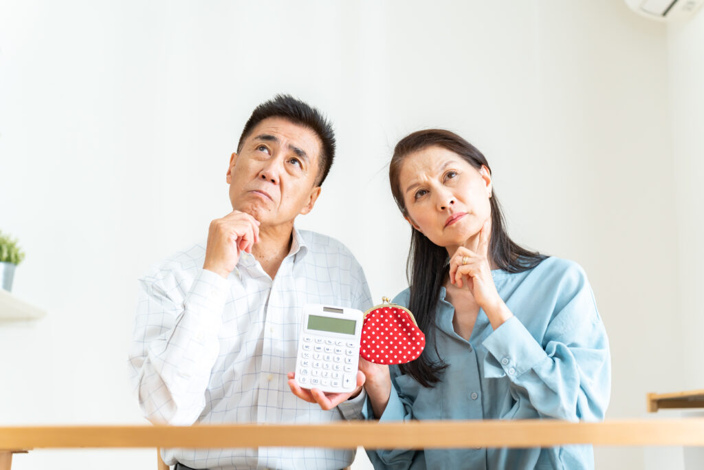財布と電卓を持って悩む夫婦
